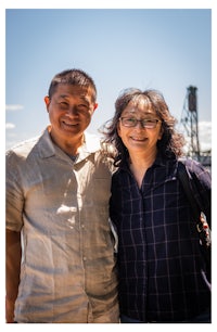 a man and woman posing for a photo in front of a building