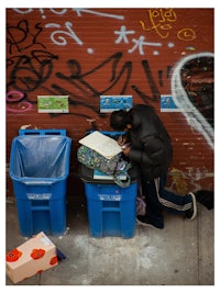 a man is putting a box into a blue trash can