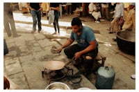 a man is cooking on a stove in front of a crowd of people