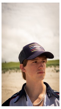 a young man wearing a baseball cap and pearls