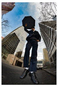 a man in a suit is holding an umbrella in the air