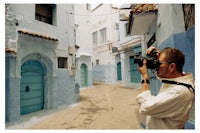 a man taking a picture in a blue alleyway