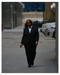 a woman in a suit walking down a sidewalk