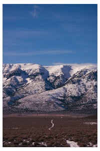 a snow covered mountain range with a dirt road in the background