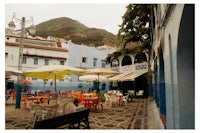 a street with tables and umbrellas in front of a mountain